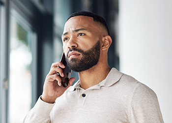 A man holding his phone to his ear and looking mildly concerned.