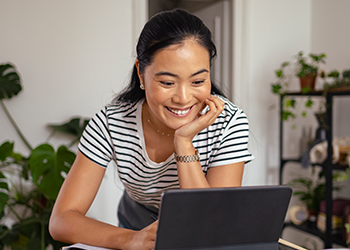 A young person smiling at their laptop