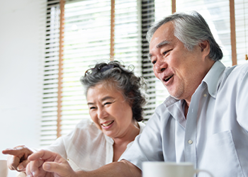 Two seniors looking at a computer screen and smiling