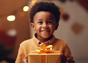 Un niño sonríe a la cámara, sosteniendo un regalo envuelto