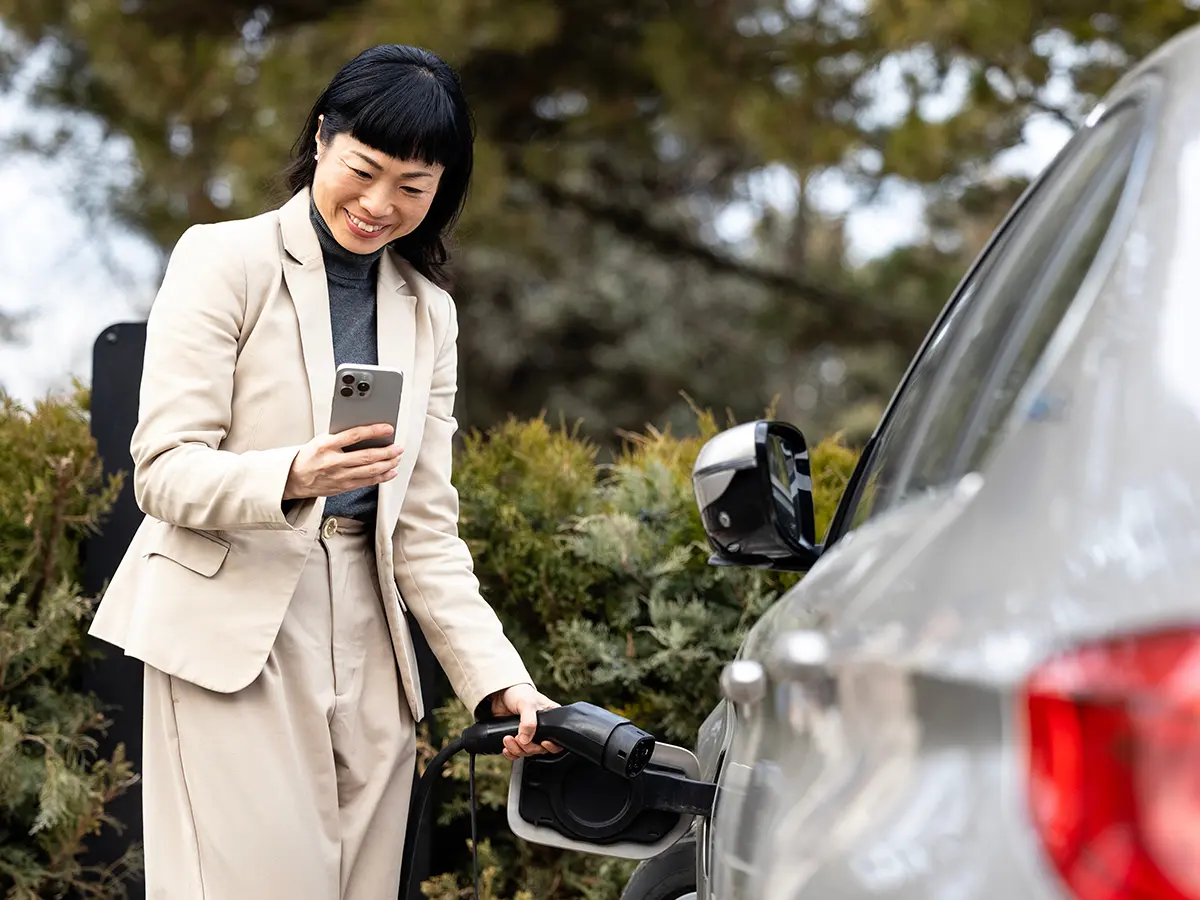 A person looking at their phone and unplugging their electric car