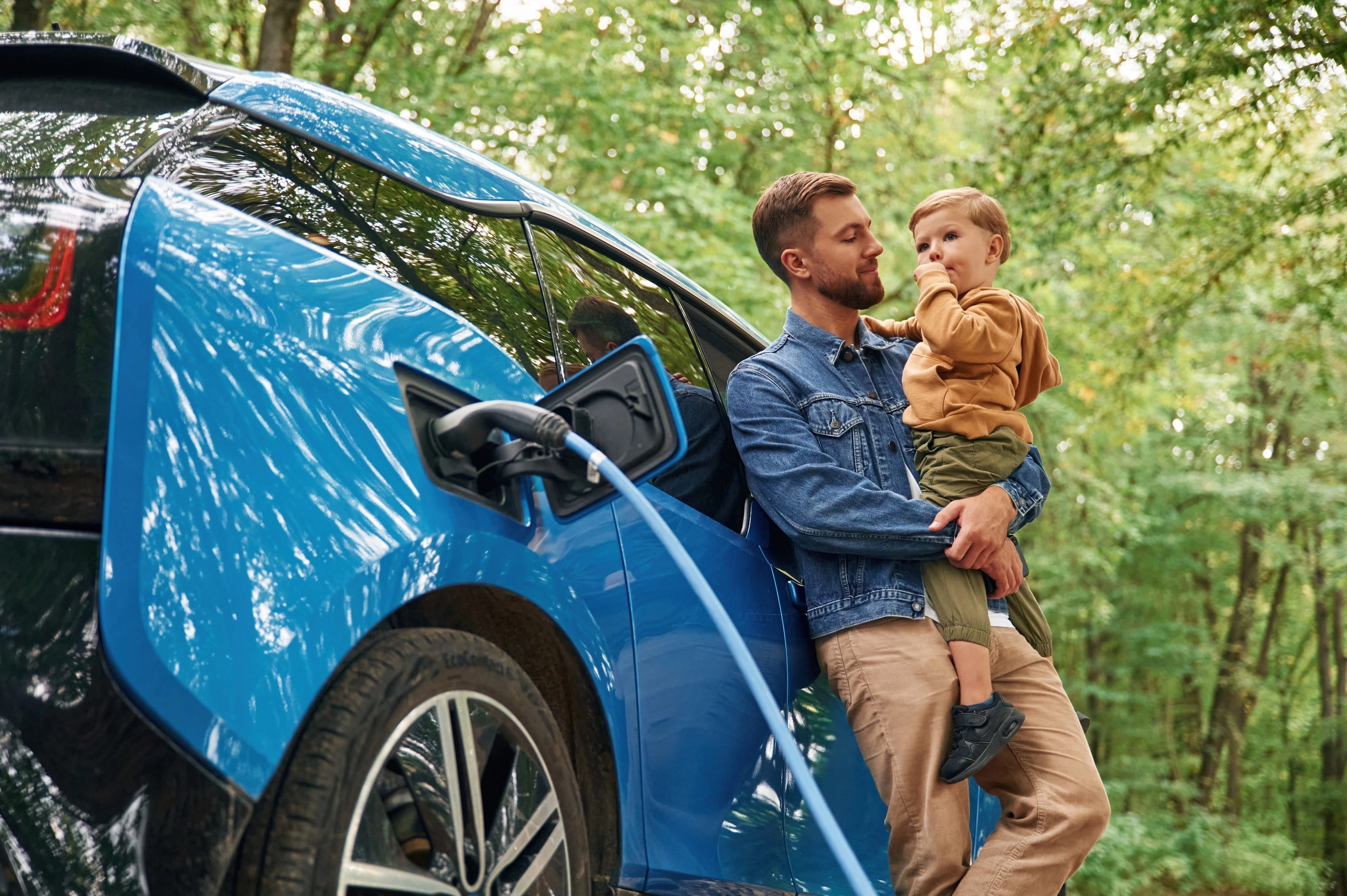 A person looking at their phone and unplugging their electric car