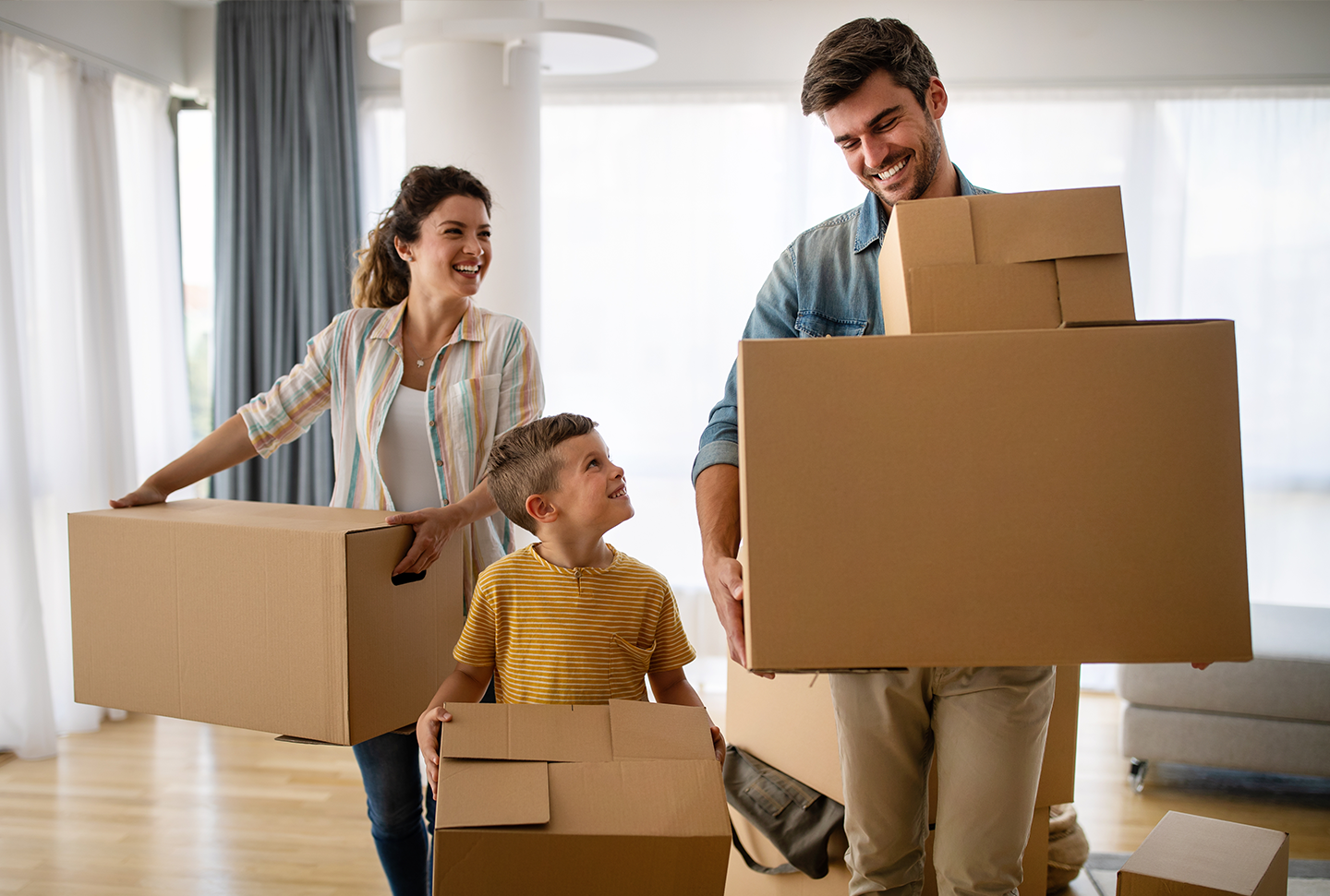 Family of three carrying cardboard boxes