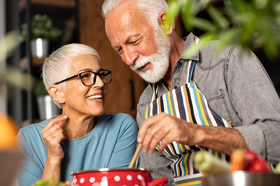 Two seniors cooking together and smiling