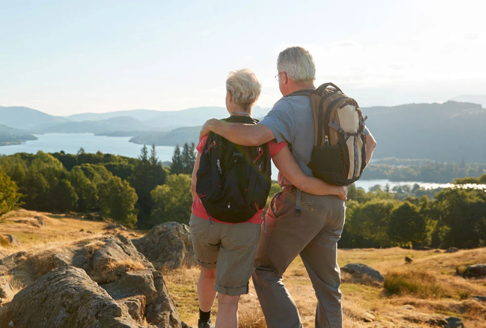 Two hikers stand looking at a mountainous view